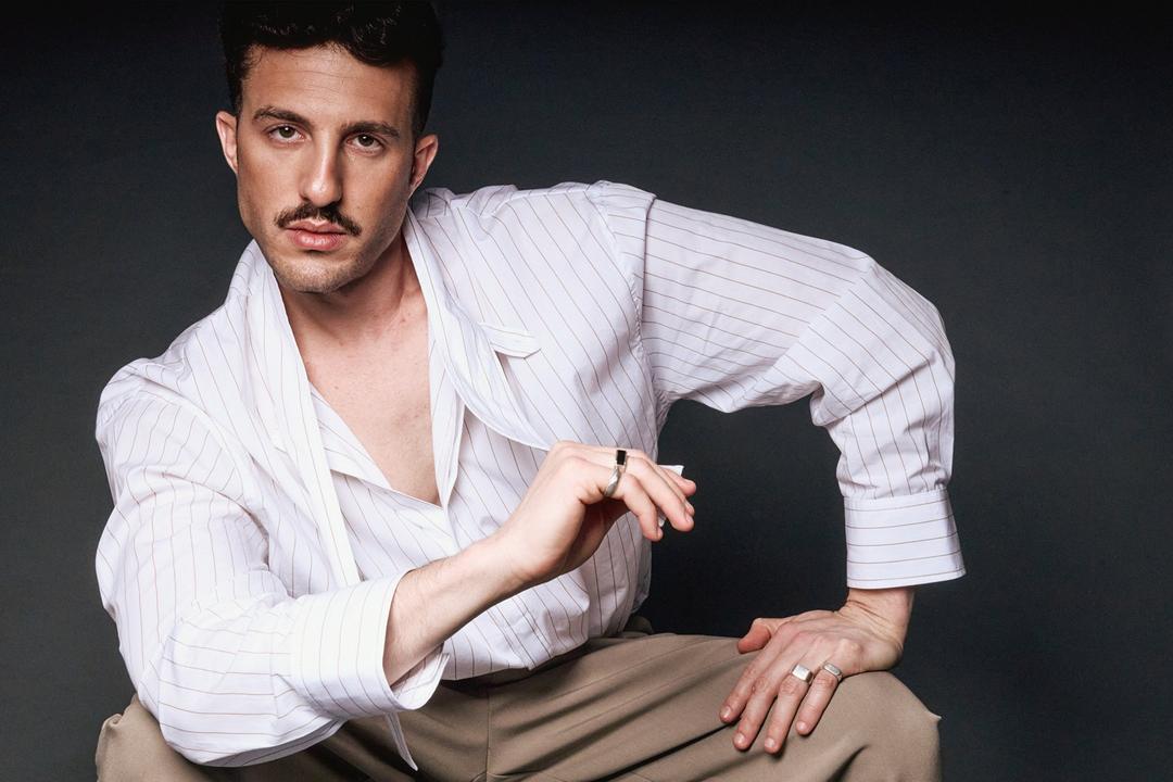 Tomer Tenenboym crouching in a white striped shirt