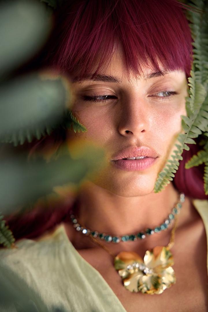 Red-haired model among ferns wearing Paula Bianco gold jewelry