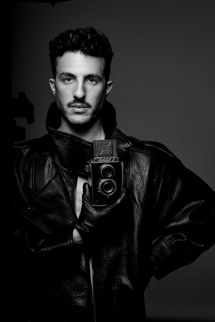 Black and white portrait of choreographer Tomer Tenenboym holding a vintage camera